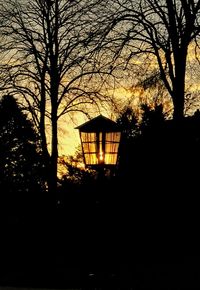 Silhouette of bare trees against sky at sunset