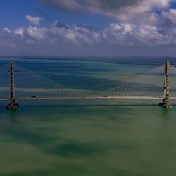 Scenic view of suspension bridge over sea against sky