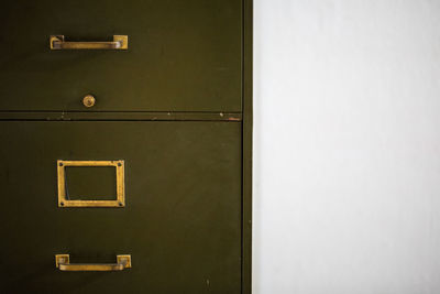 Close-up of closed cabinet against white wall