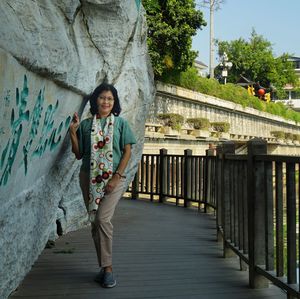 Portrait of woman standing by rock