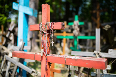 Close-up of bead necklaces on wooden cross at cemetery