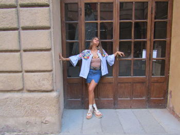 Full length portrait of a girl standing against brick wall