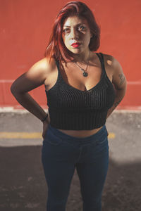 Portrait of beautiful young woman standing against red background