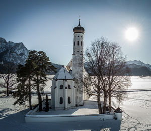 Church by building against sky during winter