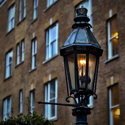 Low angle view of illuminated street light against building