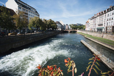 Canal amidst buildings in city against sky