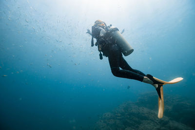 Woman swimming undersea below school of fish at del coco beach