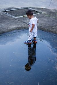 Rear view of child standing in puddle on street