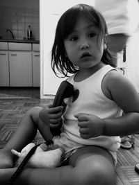 Girl holding telephone receiver while sitting on floor at home