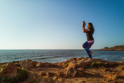 Full length of man on rocks at beach against sky