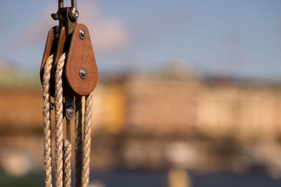 Close-up of rope tied up on wood against sky