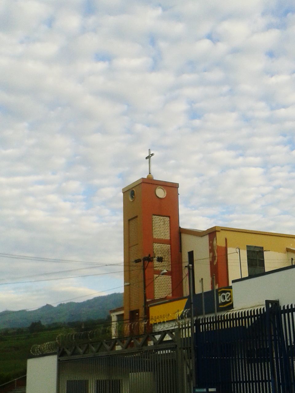 built structure, architecture, building exterior, communication, cloud - sky, sky, text, western script, tower, tall - high, cloud, mountain range, mountain, outdoors, cloudy, day, town, no people, cloudscape, tourism, residential district, history