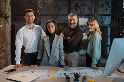 Successful team of men and women looking at camera confidently and posing in office