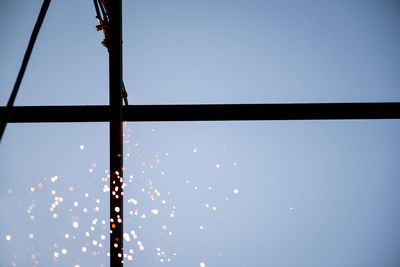 Low angle view of illuminated lights against clear blue sky