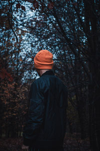 Rear view of person standing by trees in forest