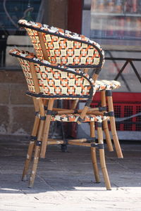 Empty chairs and tables on street against buildings in city