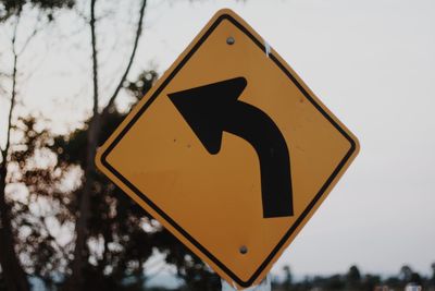 Close-up of road sign against sky