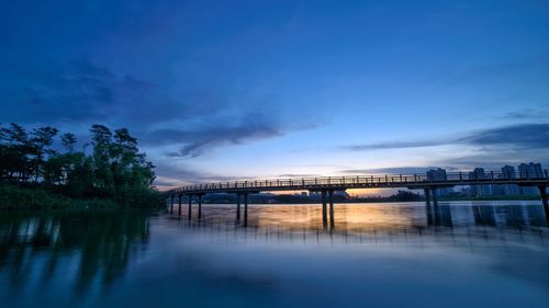 Bridge over river against blue sky at dusk