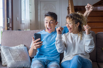 Happy friends sitting on sofa at home