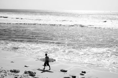 Male surfer walking on beach