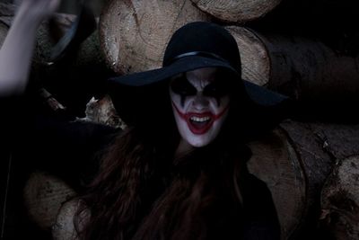 Portrait of woman in zombie make-up making face against logs