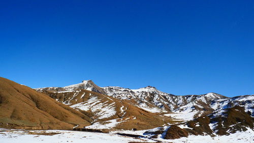 Scenic view of snowcapped mountains against clear blue sky