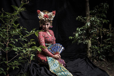 Woman wearing traditional clothing kneeling in forest