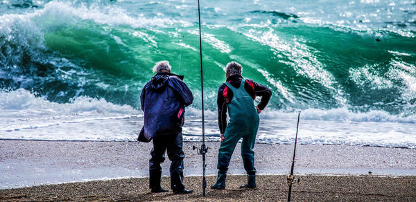 Rear view of men standing at beach