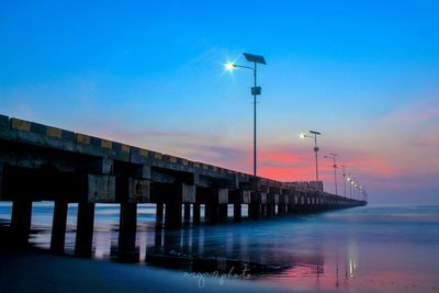 Bridge over sea against sky during sunset