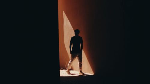 Rear view of silhouette man standing against door