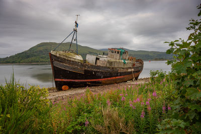 Boat moored on beach against sky