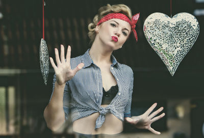 Portrait of woman blowing kiss through glass window