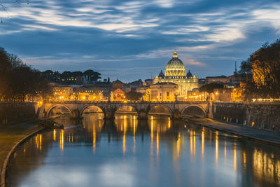 Tiber river by st peter basilica against sky at dusk