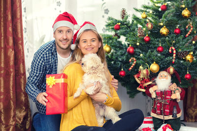 Portrait of smiling young woman with christmas tree during winter