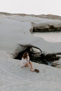 Young woman sitting on rock at beach