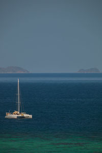 Sailboat sailing on sea against clear sky