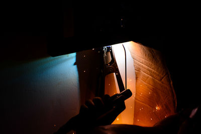 Cropped image of welder hand welding in darkroom