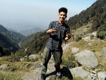 Portrait of smiling young man standing on top of mountain