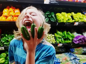 Portrait of girl making face while holding vegetable at supermarket