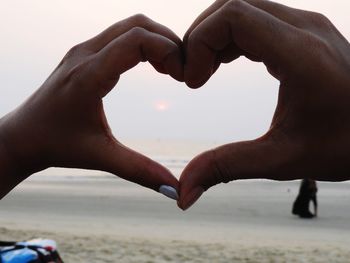 Midsection of heart shape on beach against sea