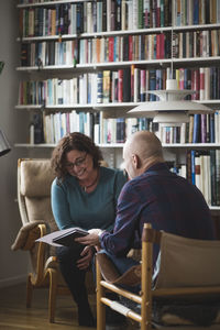 Male therapist showing document to smiling patient at home office