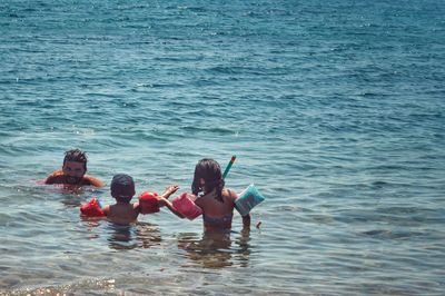 Shirtless father with children in sea