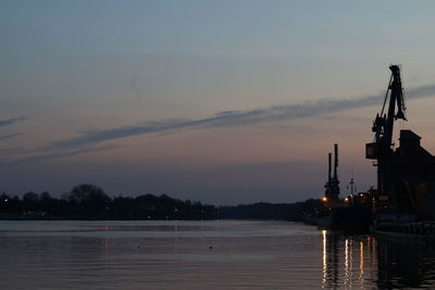 Silhouette of commercial dock against sky during sunset