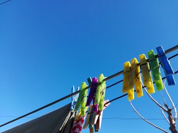 Clothespins hanging on clothesline against clear blue sky