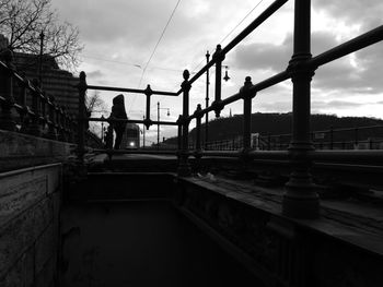 People on bridge in city against sky