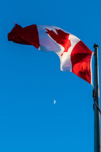 Low angle view of flag against blue sky