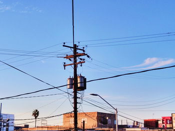 Low angle view of electricity pylon against blue sky