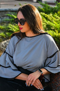 Young woman wearing sunglasses sitting outdoors