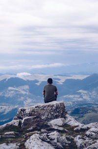 Rear view of man sitting on rock