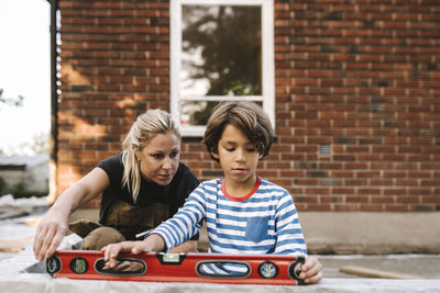 Mother and son using level while expanding house during summer